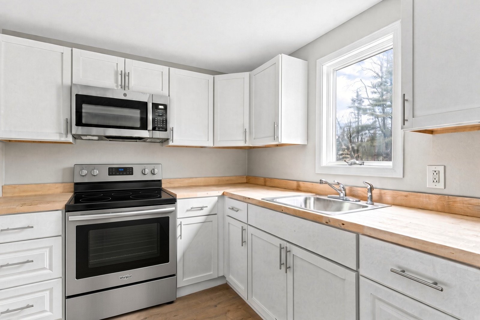 Renovated kitchen with white cabinets and stainless appliances