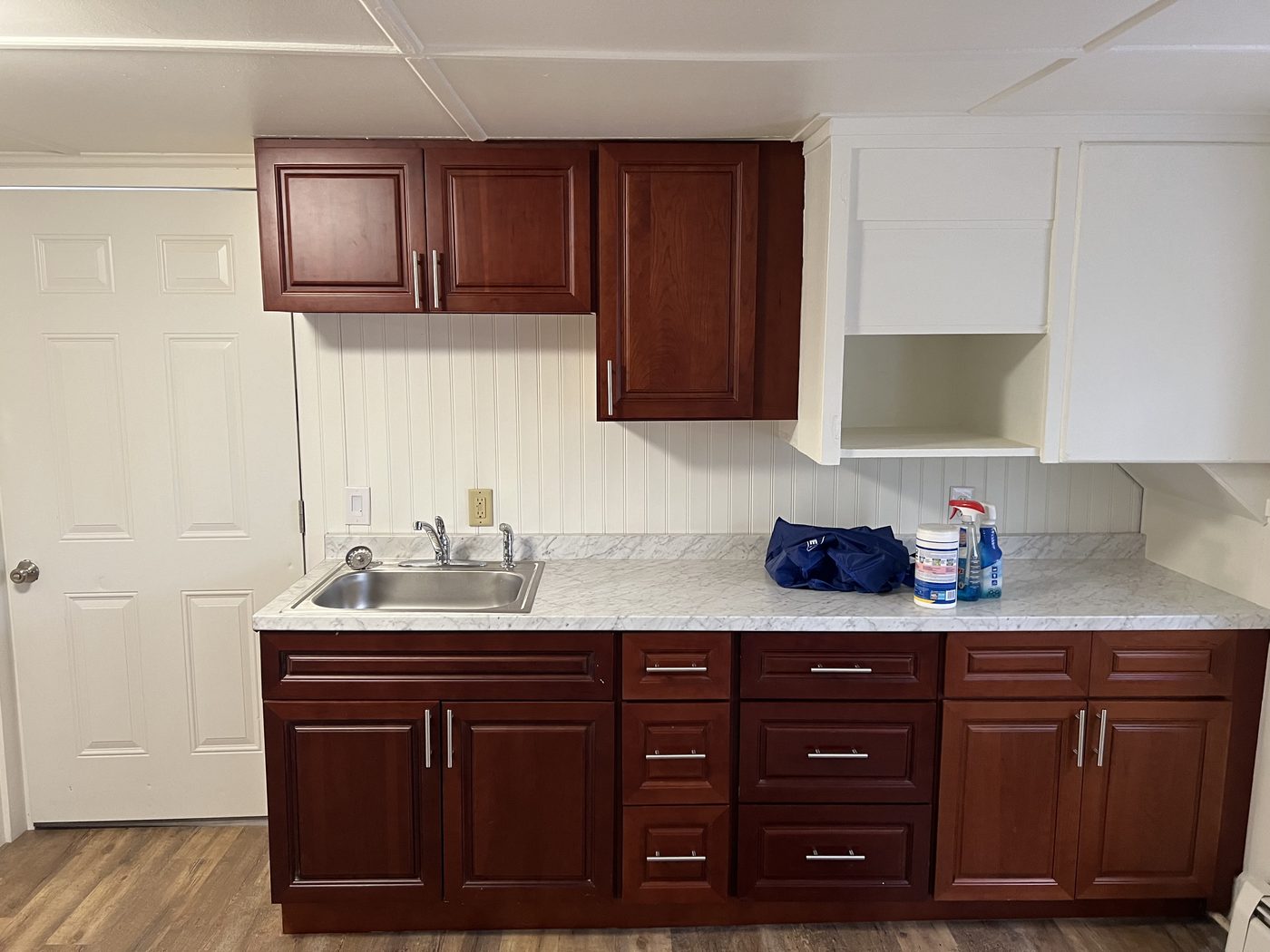 Renovated kitchen at 9 Bodwell Street with cherry cabinets, white countertops and new flooring