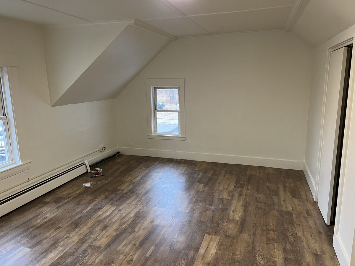 Renovated room at 9 Bodwell Street with new wood-look flooring and a window